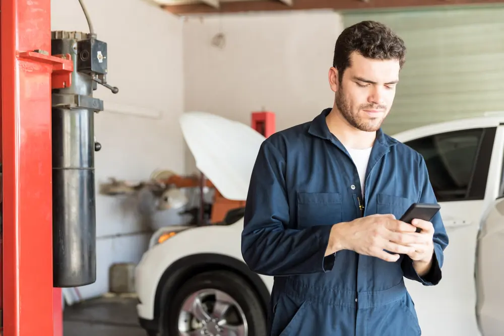 Mechanic checking his phone in an auto repair shop